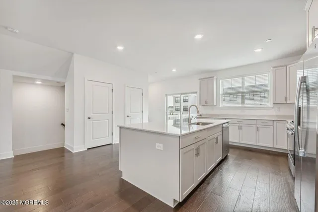 a kitchen with white cabinets appliances and wooden floor