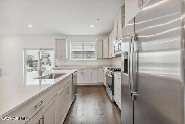a kitchen with kitchen island granite countertop a sink stainless steel appliances and cabinets