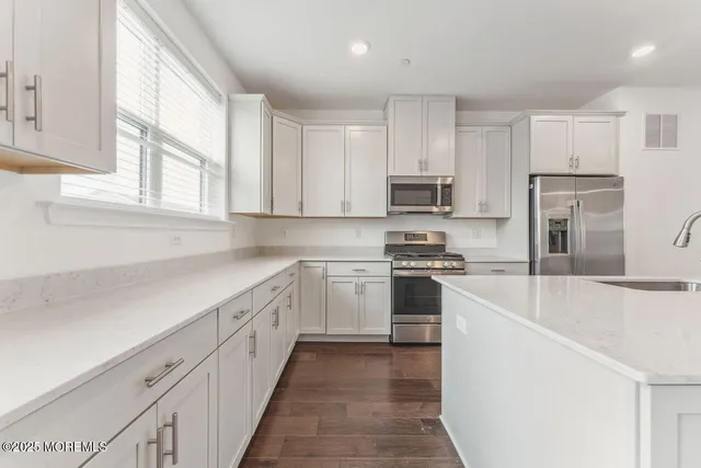 a kitchen with granite countertop white cabinets and stainless steel appliances