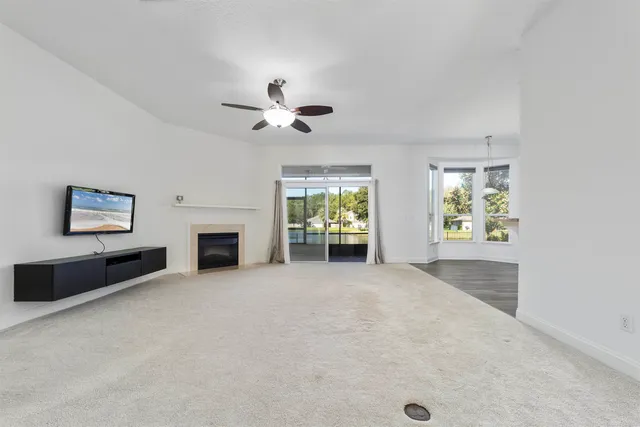 an empty room with windows and ceiling fan
