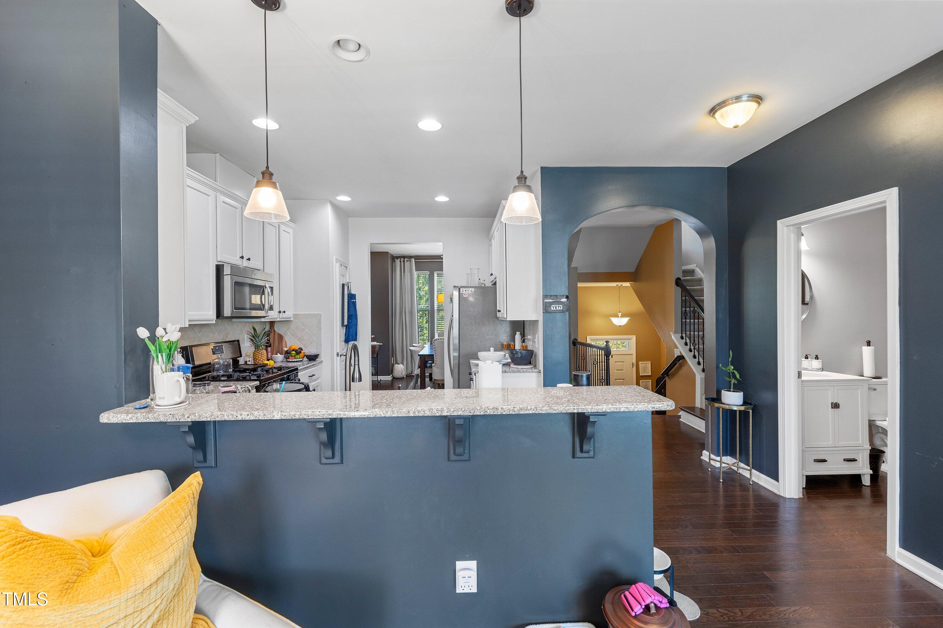 9352 Wooden Road Raleigh, NC 27617 - Photo 13 of 43 a room with stainless steel appliances a kitchen island a chandelier a large window and a kitchen view