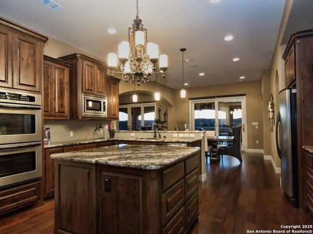 a kitchen with stainless steel appliances granite countertop a kitchen island a stove and a sink