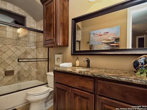 a bathroom with a granite countertop sink a toilet and a mirror