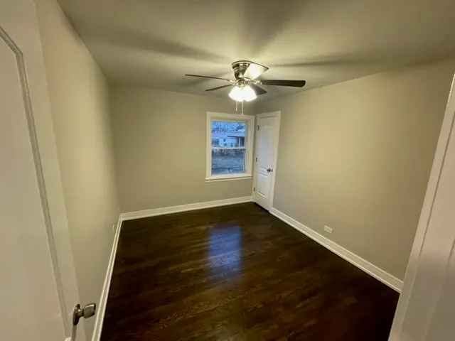 an empty room with wooden floor fan and window