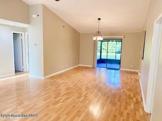 a view of an empty room with window and wooden floor
