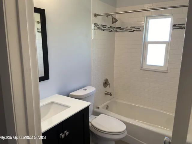 a bathroom with a sink a toilet a mirror and shower