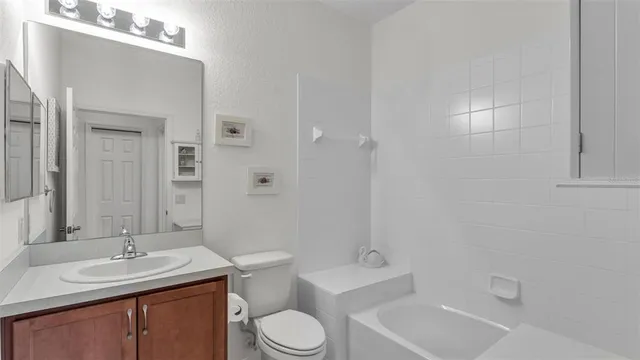 a bathroom with a toilet a sink a tub and mirror