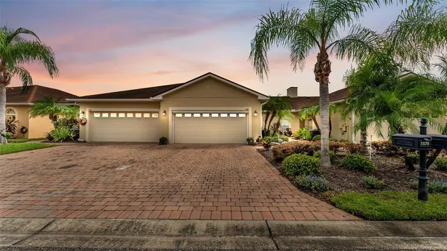 a front view of a house with a yard and palm trees