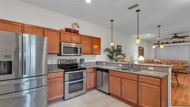 a kitchen with stainless steel appliances granite countertop a refrigerator a stove a sink and a microwave