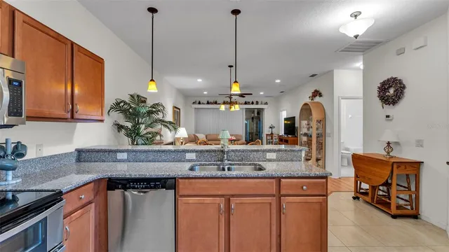 a kitchen with stainless steel appliances granite countertop a sink a stove and a wooden cabinets