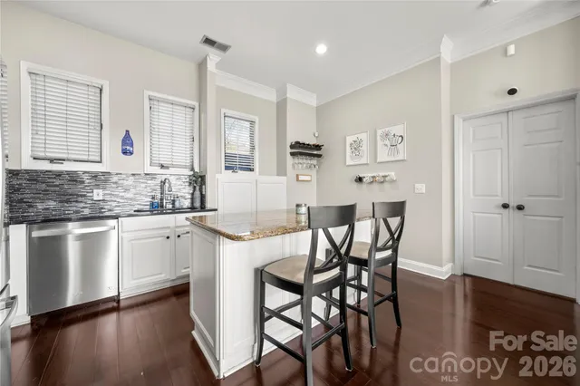 a kitchen with stainless steel appliances granite countertop a table chairs sink and cabinets