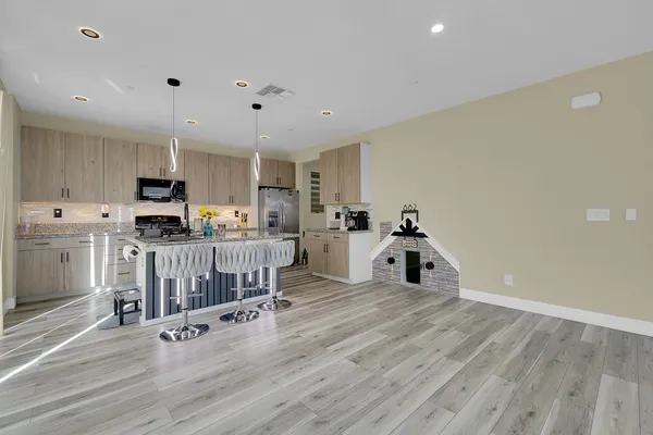 a kitchen with stainless steel appliances a stove a sink dishwasher a refrigerator white cabinets with wooden floor