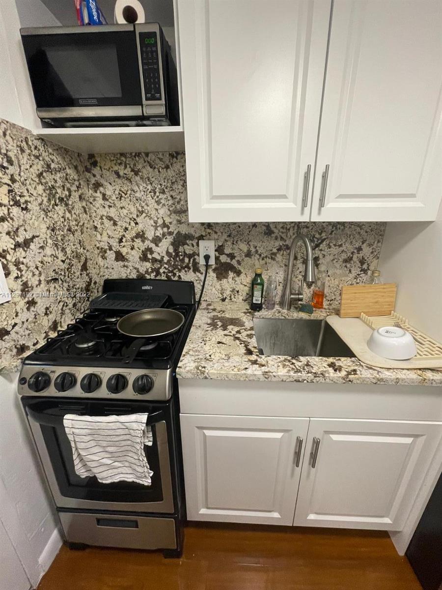 North Beach Miami, FL 33141 - Photo 3 of 10 a kitchen with granite countertop a stove and a microwave
