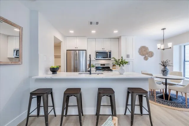 a kitchen with white cabinets and chairs