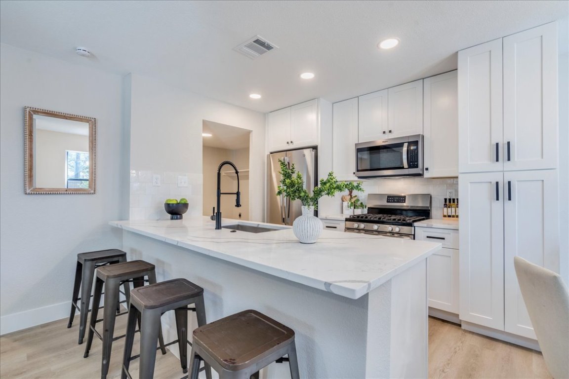 11301 Jollyville Road, Unit F2 Austin, TX 78759 - Photo 8 of 29 a kitchen with sink a microwave a stove and refrigerator with wooden floor
