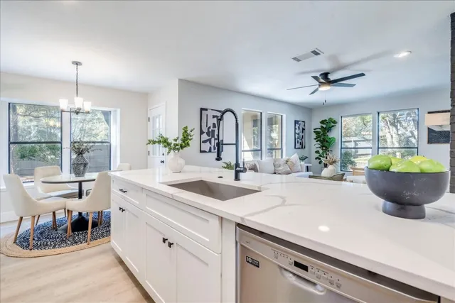 a large white kitchen with a sink and a large window
