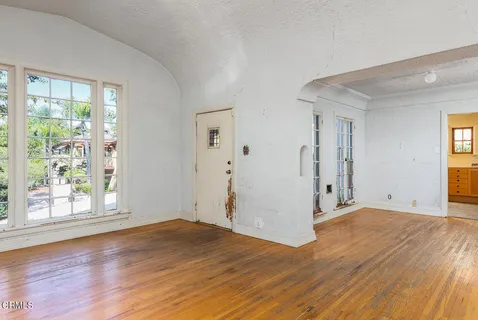 a view of empty room with wooden floor and fan
