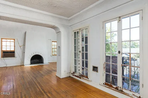 a view of an empty room with window and wooden floor
