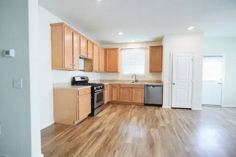 a kitchen with white cabinets a sink a window and stainless steel appliances