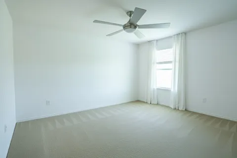 an empty room with a window and a fan