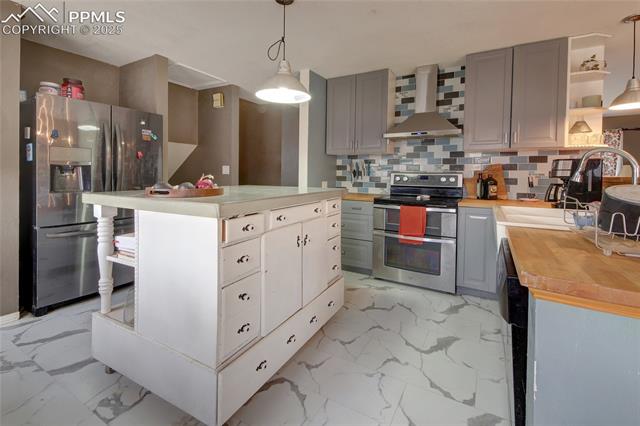 Kitchen with marble finish floor, gray cabinets, wall chimney exhaust hood, and appliances with stainless steel finishes