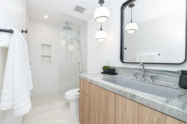 a bathroom with a granite countertop sink a toilet and a large mirror