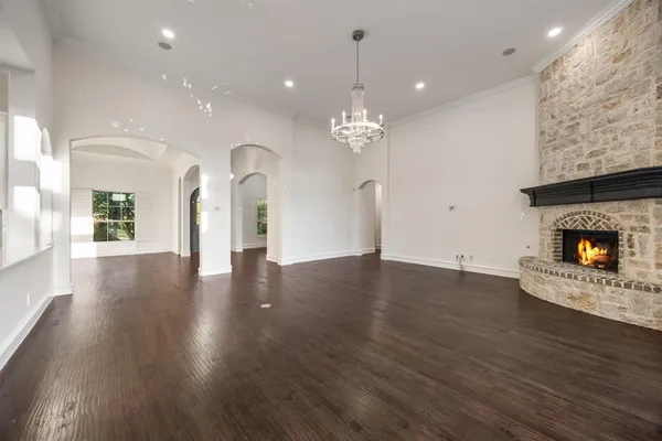 an empty room with wooden floor a fireplace a potted plant and a chandelier