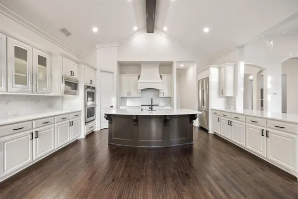 a large white kitchen with stainless steel appliances granite countertop a stove a sink dishwasher and a oven with white cabinets