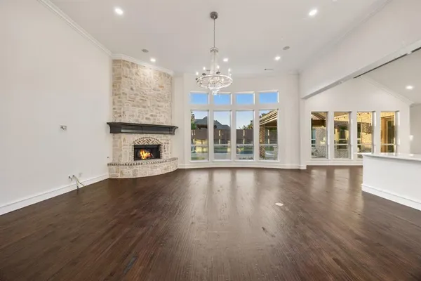 an empty room with wooden floor fireplace cabinet and windows