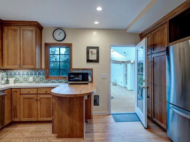 a kitchen with stainless steel appliances granite countertop a refrigerator a sink dishwasher a stove and a refrigerator with wooden floor