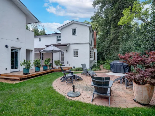 a view of a patio with table and chairs potted plants and large tree