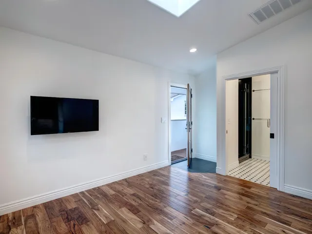 a view of an empty room with wooden floor and windows