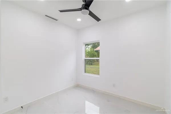 an empty room with a window and a fan