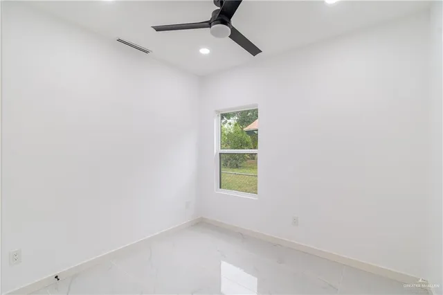 an empty room with a window and a fan