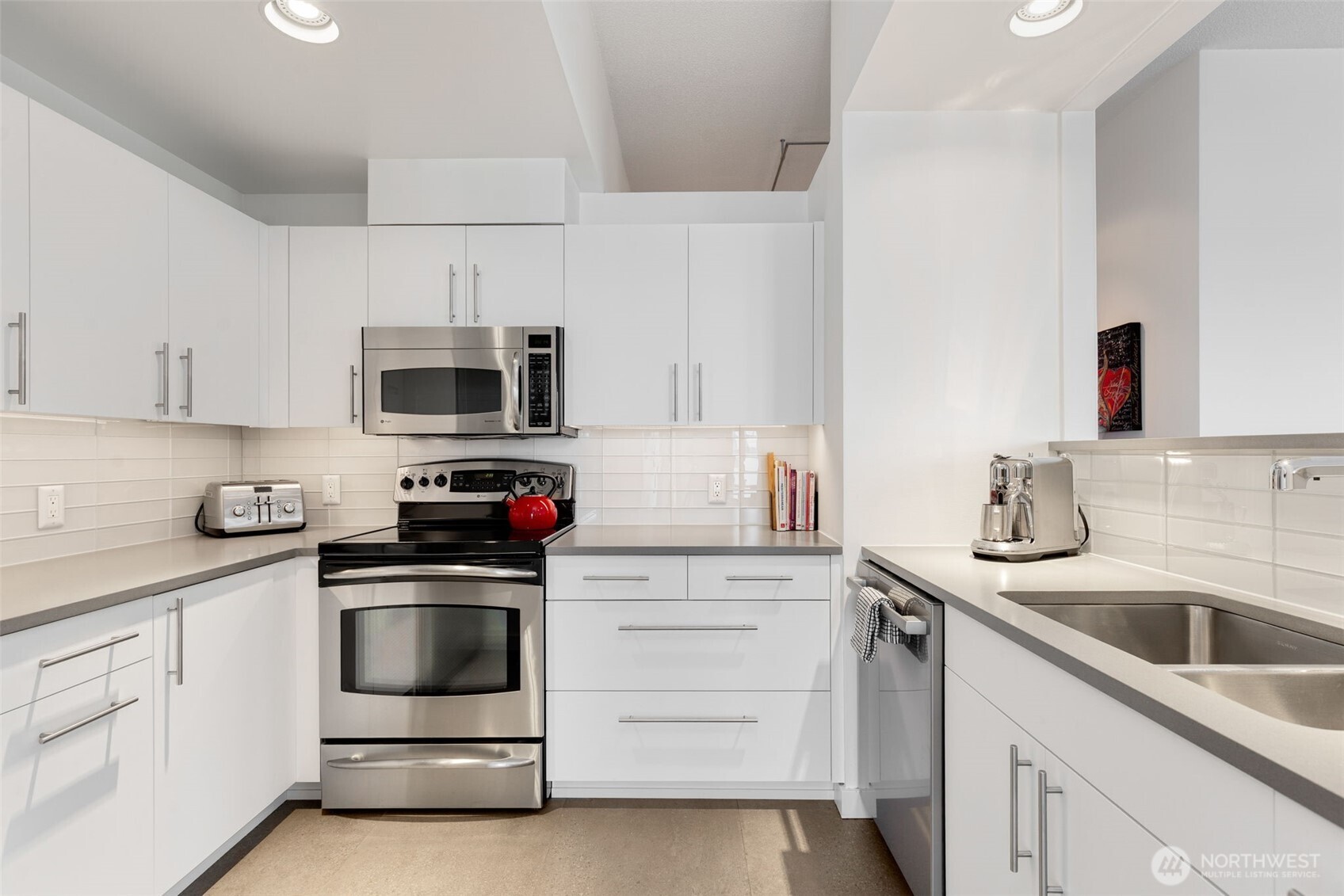 98 Union Street, Unit 206 Seattle, WA 98101 - Photo 13 of 35 a kitchen with white cabinets stainless steel appliances and sink