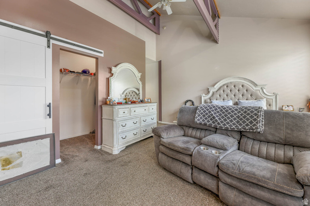 569 Elk Meadow Loop Tooele, UT 84074 - Photo 25 of 56 Carpeted bedroom with a barn door, a walk in closet, and a high ceiling