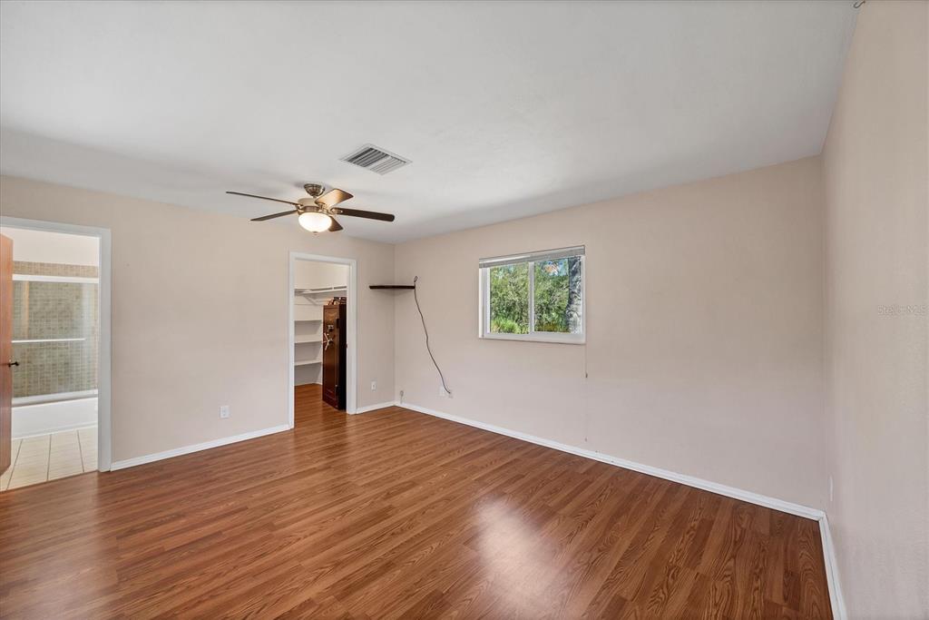 1135 Range Road Englewood, FL 34224 - Photo 24 of 42 an empty room with wooden floor chandelier fan and windows