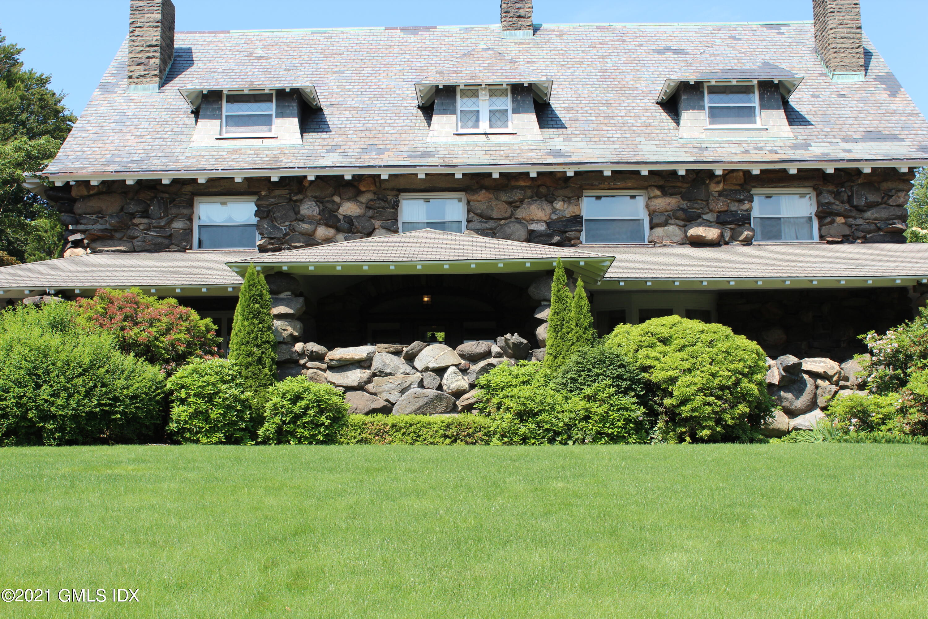 432 Field Point Road Greenwich, CT 06830 - Photo 2 of 56 a front view of a house with a garden