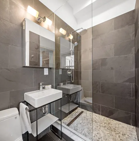 a bathroom with a sink a toilet a mirror and shower