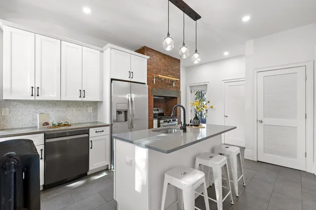 a kitchen with kitchen island granite countertop a sink cabinets and stainless steel appliances