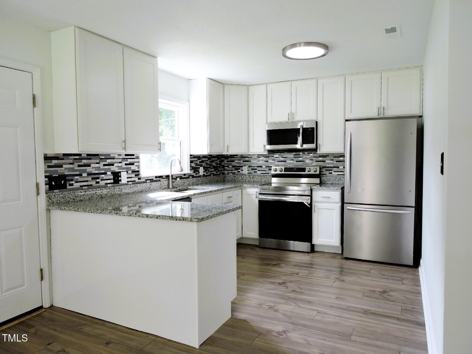 1620 Riddle Road Durham, NC 27713 - Photo 4 of 28 a kitchen with granite countertop a refrigerator stove a sink and dishwasher with wooden floor