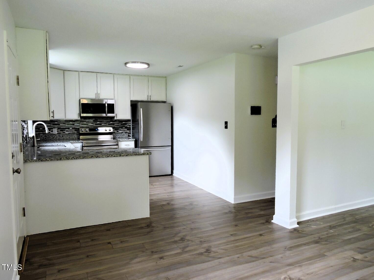 1620 Riddle Road Durham, NC 27713 - Photo 10 of 28 a kitchen with stainless steel appliances granite countertop a refrigerator sink and white cabinets