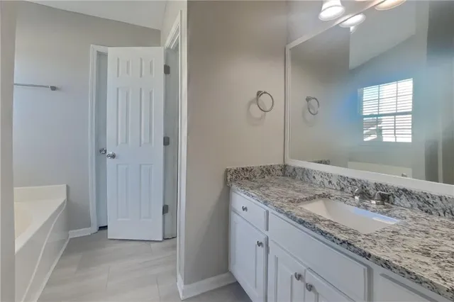a bathroom with a granite countertop sink a mirror and a bathtub