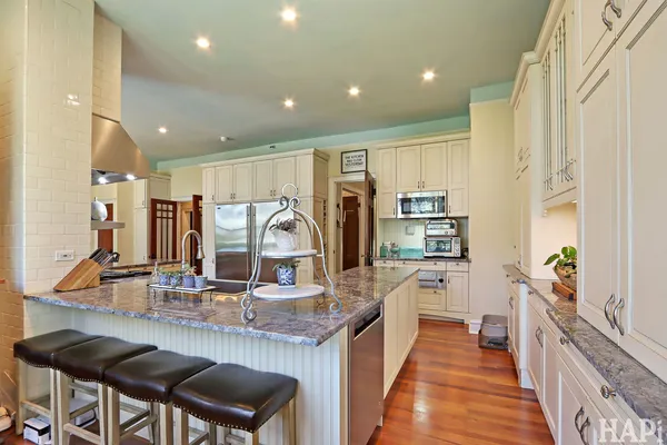 a living room with stainless steel appliances granite countertop furniture and a wooden floor