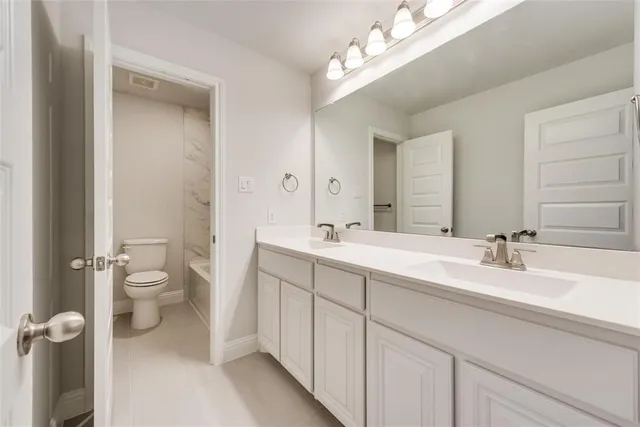 a bathroom with a double vanity sink toilet and a mirror