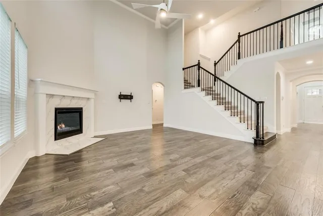 a view of an empty room with wooden floor and a fireplace