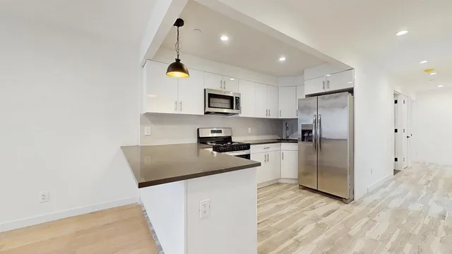 a kitchen with stainless steel appliances granite countertop a refrigerator a stove a sink dishwasher and a refrigerator with wooden floor