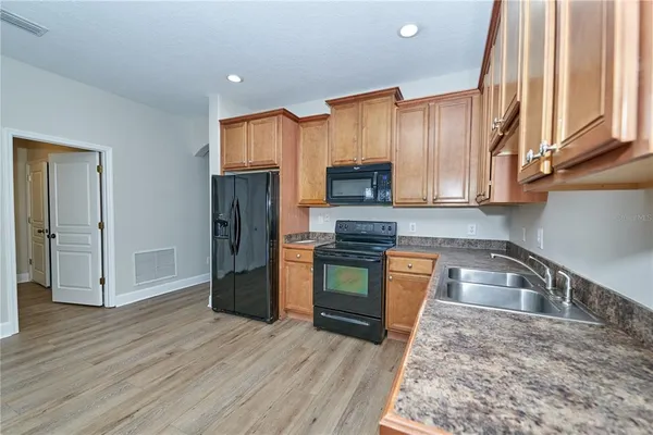 a kitchen with granite countertop a stove a sink and a refrigerator