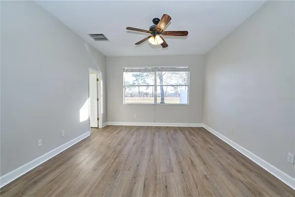 a view of empty room with wooden floor and ceiling fan