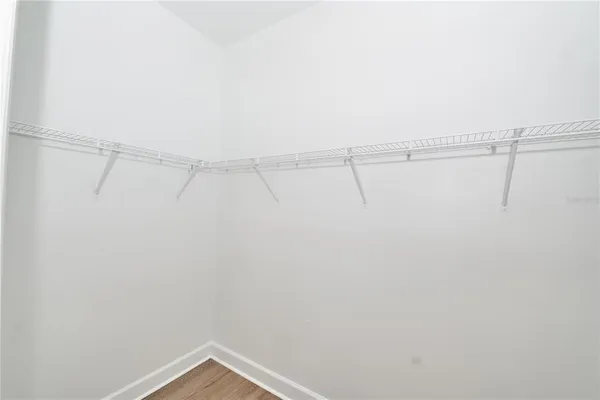 an empty room with wooden floor ceiling fan and windows